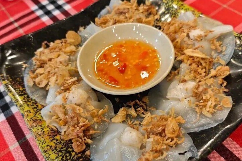 A plate of spring rolls with a dipping sauce and fried shallots. 5