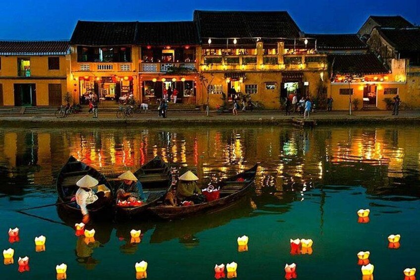 A traditional building with a reflection in the water, a boat with people, and floating lanterns. 4