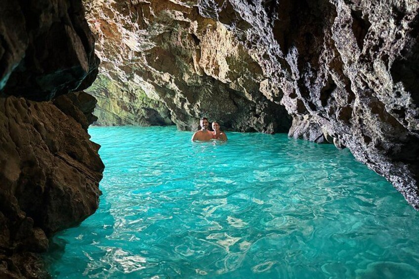 A person swimming in a turquoise cave pool. 2