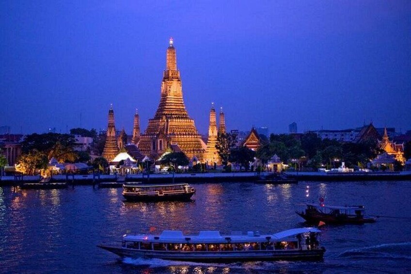 A temple complex at dusk with illuminated structures and boats on the water. 5