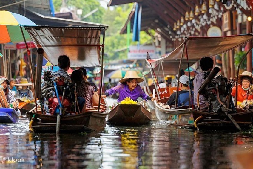 A group of people in traditional boats on a waterway, with a covered structure in the background. 2
