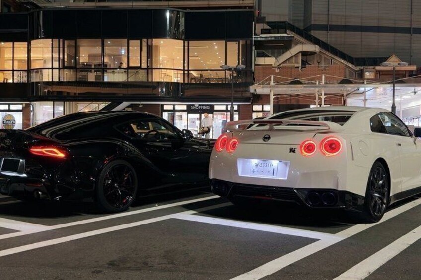 Two sports cars parked on a city street at night. 2