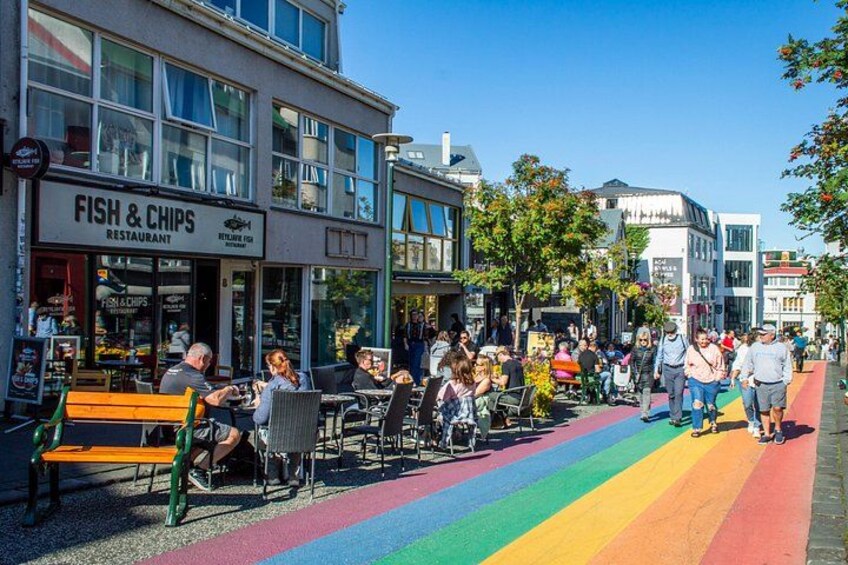 A street with outdoor seating, a rainbow-colored path, and a restaurant named 'Fish & Chips'. 4