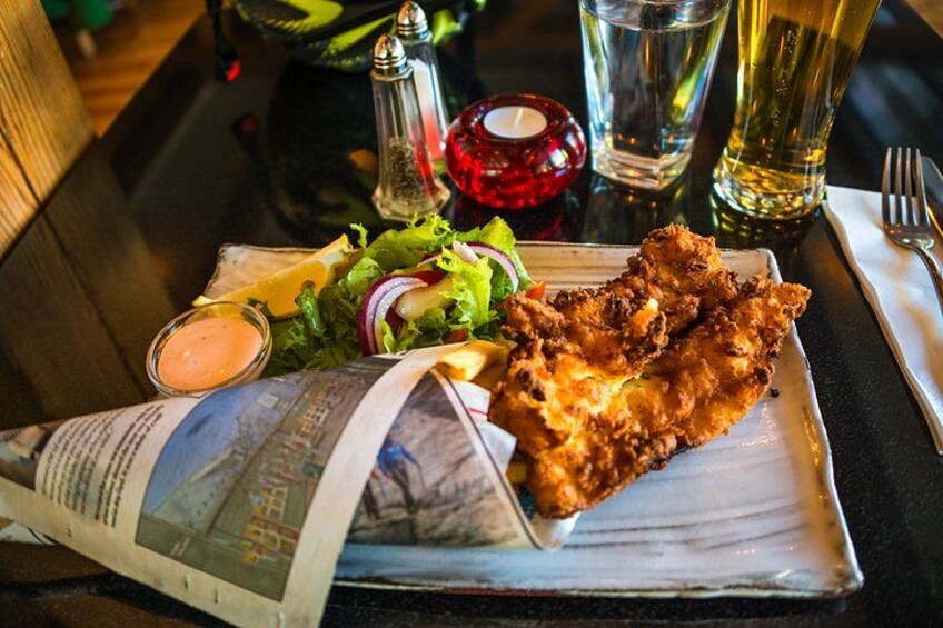 A meal with fried chicken, salad, and a newspaper on a table. 1