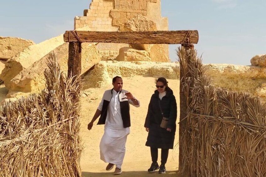 Two people walking through an ancient Egyptian gateway with a pyramid in the background. 1