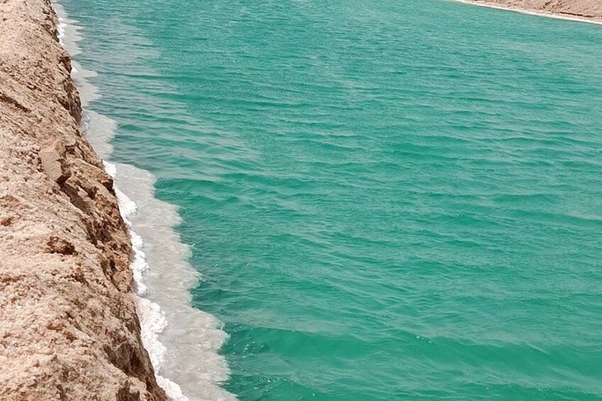 A coastal landscape with a rocky shoreline and turquoise sea. 3