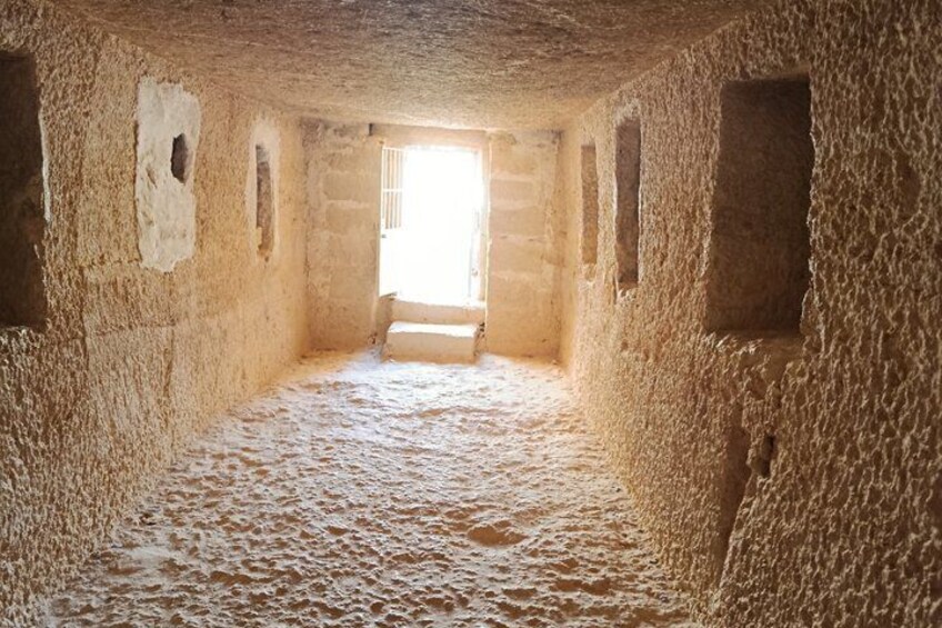 A narrow, dimly lit passageway with rough walls and a rough, uneven floor. 5