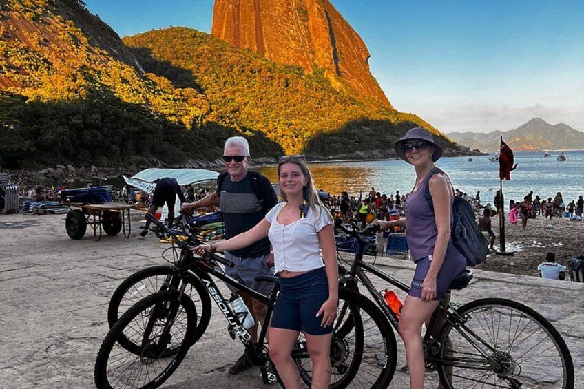 A beach with people, bicycles, and a large mountain in the background. 1