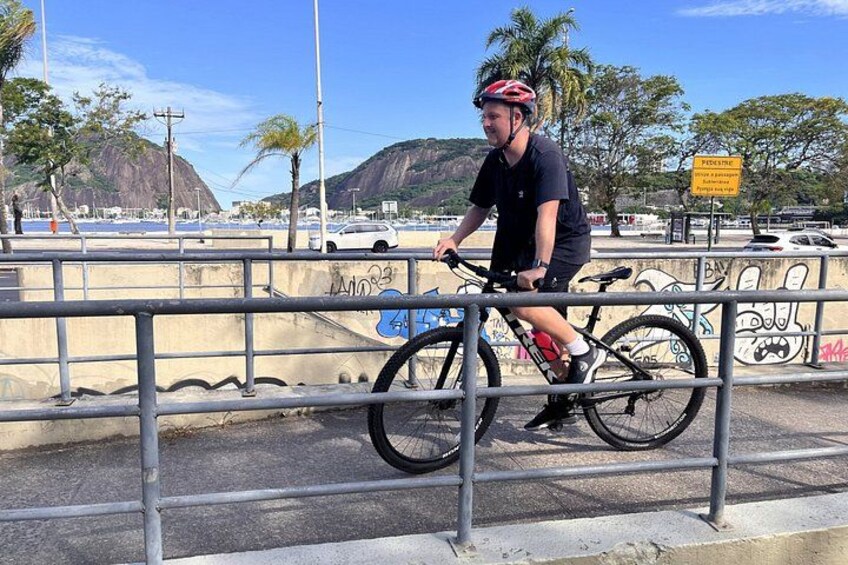 A person riding a bicycle on a bridge with graffiti on the walls and a mountain in the background. 2