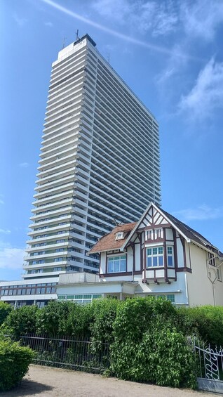 A modern high-rise building with a traditional house in the foreground. 3