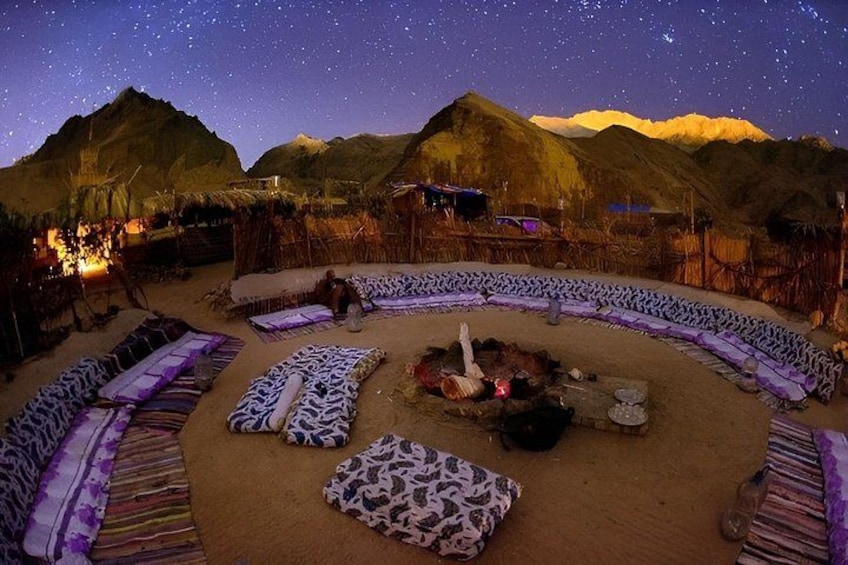 A starlit night scene with a circular seating area and a fire pit. 2
