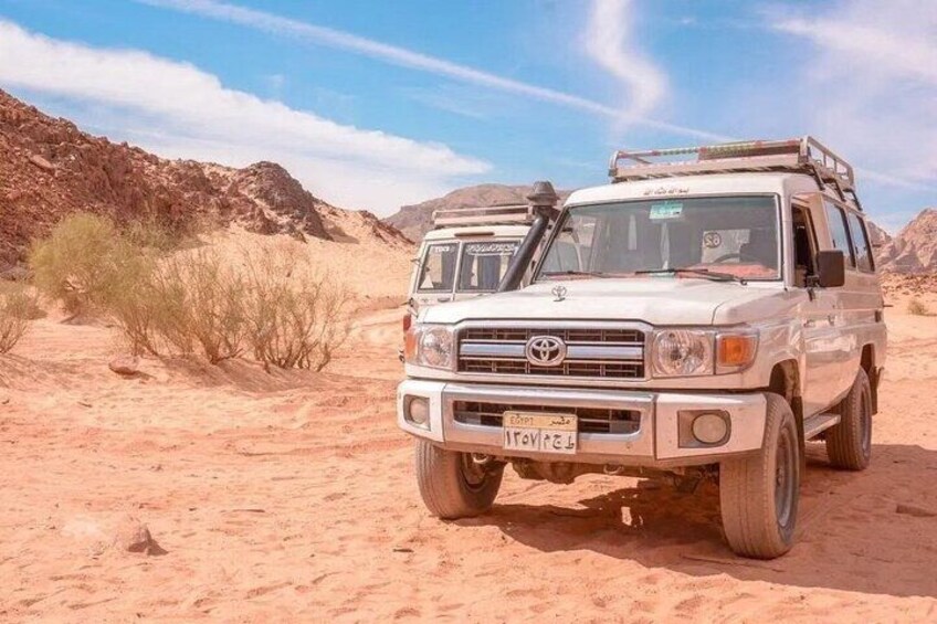 A white off-road vehicle in a desert with rocky terrain and sparse vegetation. 3