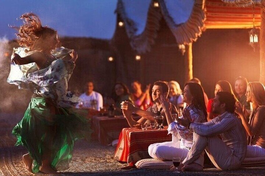 A person dancing in a traditional outfit, a group of people sitting at a table with drinks, and a building with a thatched roof in the background. 5