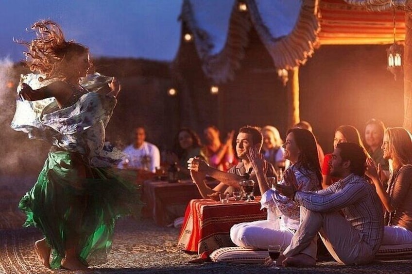 A person dancing in a green skirt, a group of people sitting at a table with drinks, and a traditional building in the background. 5