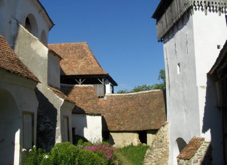 A historic building with a tiled roof, white walls, and a stone base. 2