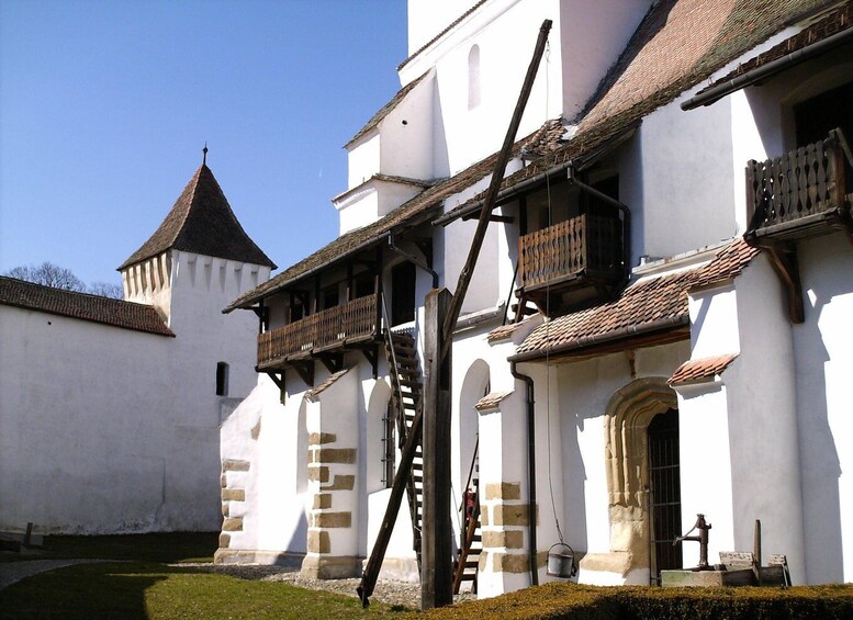 A historic building with white walls, wooden balconies, and a traditional tiled roof. 5