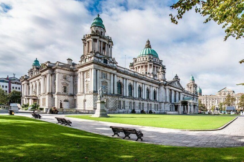 A large classical building with domed roofs and a central dome, surrounded by a well-maintained lawn and a paved walkway. 2