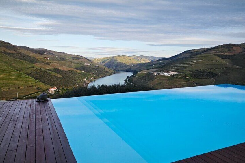 A wooden deck overlooking a swimming pool with a scenic view of a valley and lake. 1