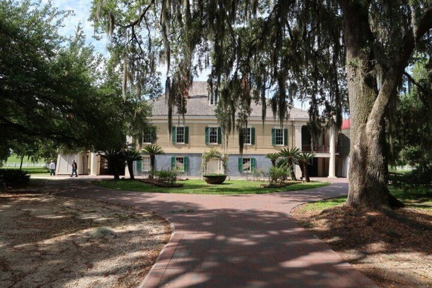A historic building with a red pathway leading to it, surrounded by trees and a well-maintained lawn. 3