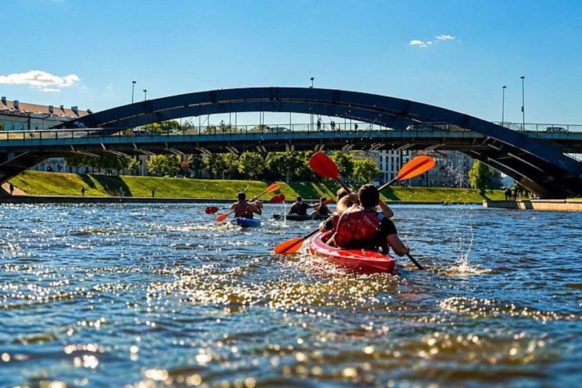 People kayaking on a river with a bridge in the background. 1