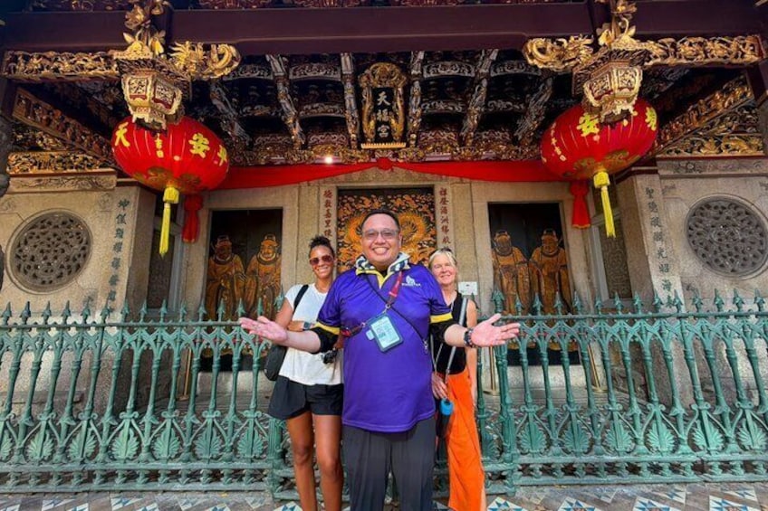 A temple with ornate golden decorations, red lanterns, and a green iron fence. 3