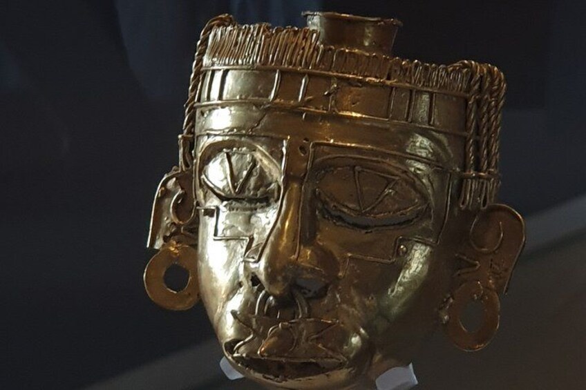 A gold-colored artifact with intricate designs and circular holes. 3