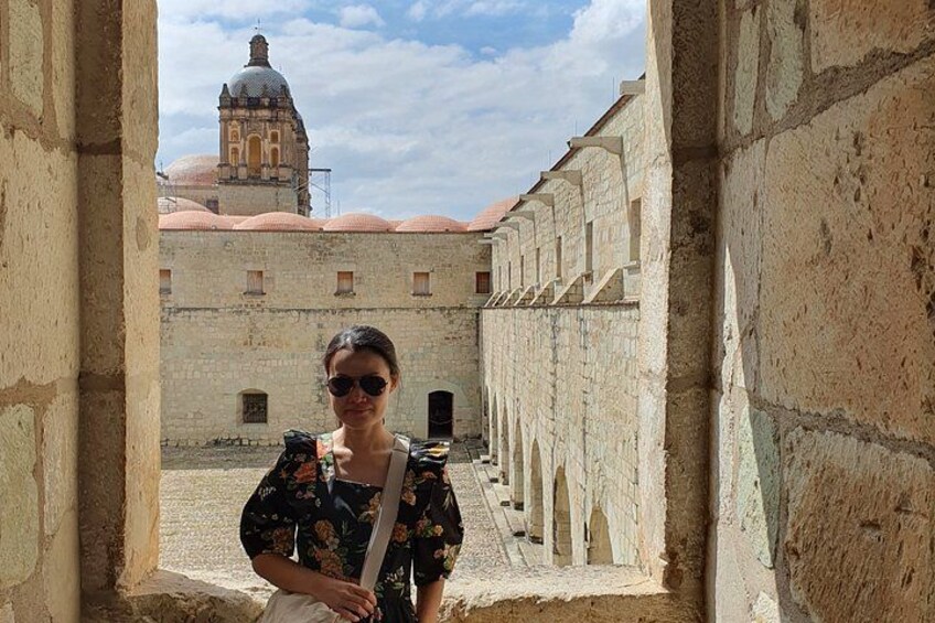 A person standing in an ancient stone corridor with a historic building in the background. 4