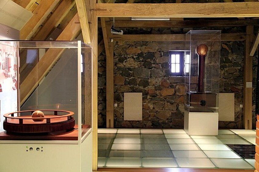 A room with a stone wall, a wooden ceiling, and a glass display case with a circular object. 2