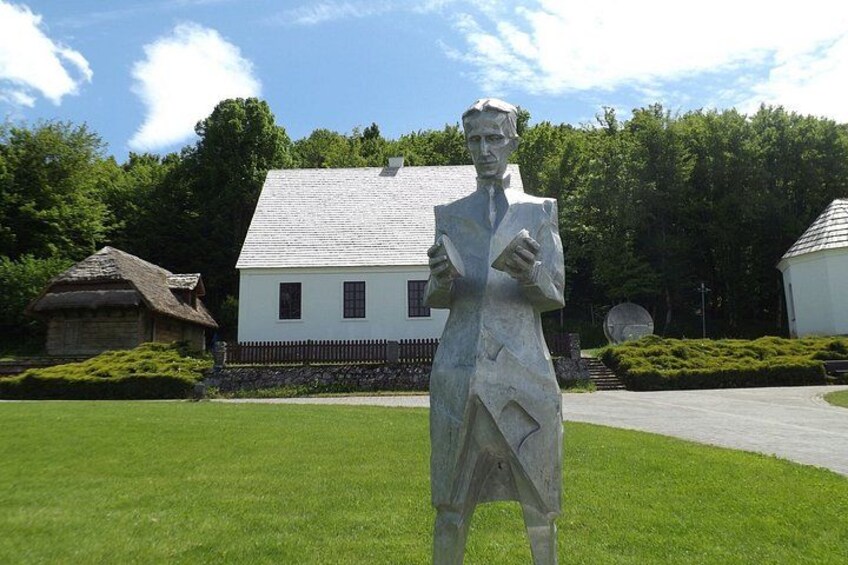 Una statua di un uomo in abito, una casa bianca e un edificio con tetto di paglia. 2