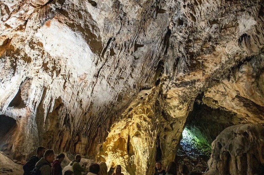 A cave interior with stalactites and stalagmites, illuminated by artificial lighting. 3