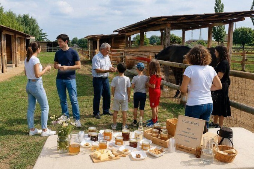 A group of people at a farm with a picnic table set up with food and honey jars. 1