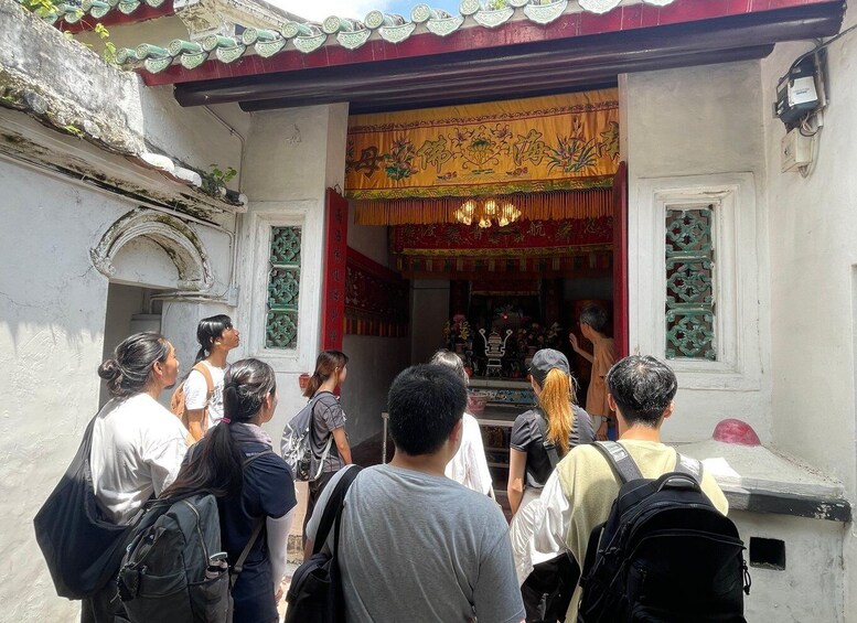 A group of people visiting a temple with traditional architecture and a red and gold entrance. 1