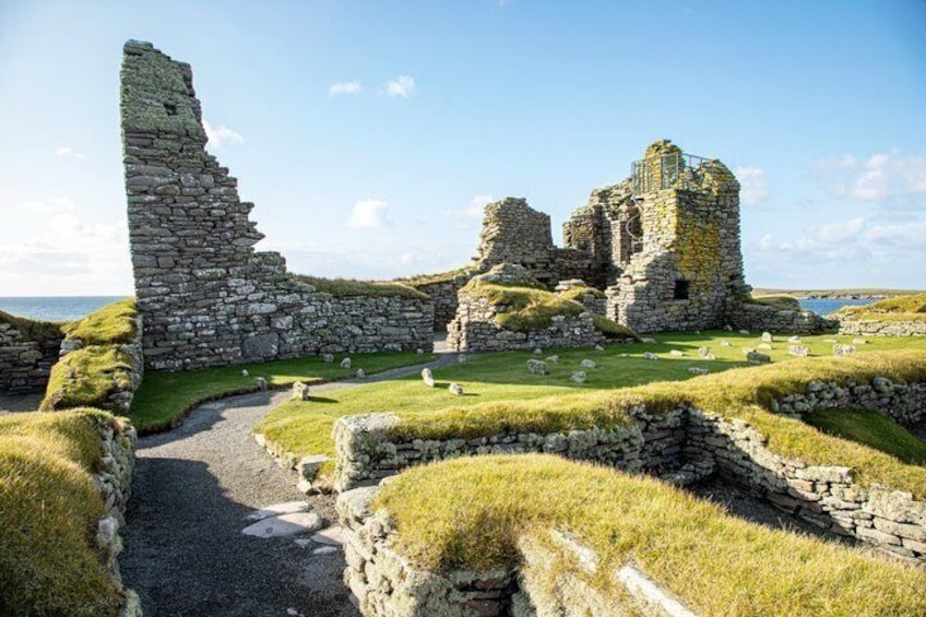 Ancient stone ruins with grassy paths and a clear sky. 1