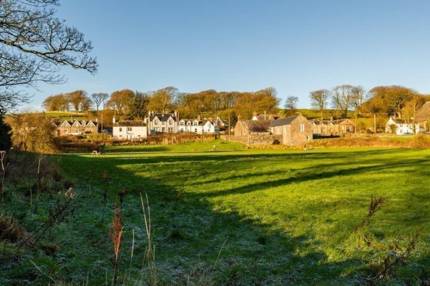 A rural village with stone houses and a grassy field. 2