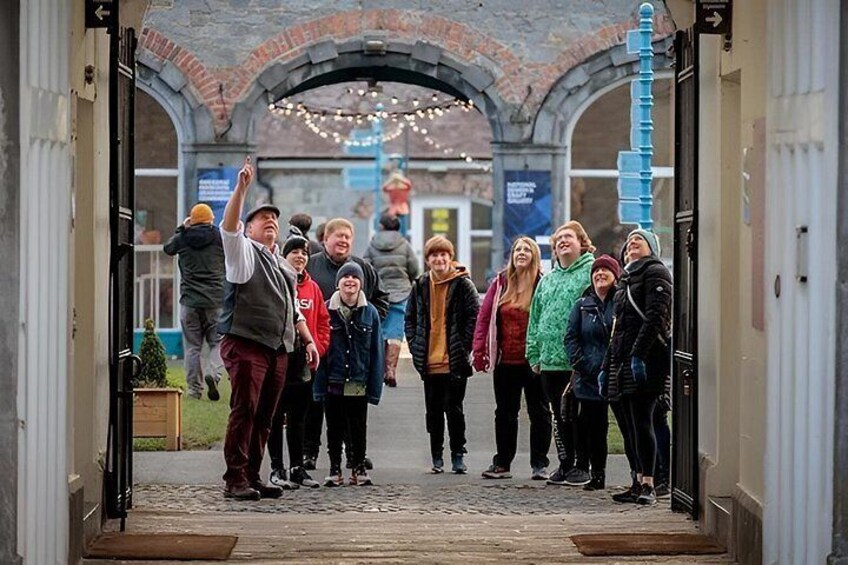 A group of people standing in a doorway with a brick archway and string lights in the background. 3