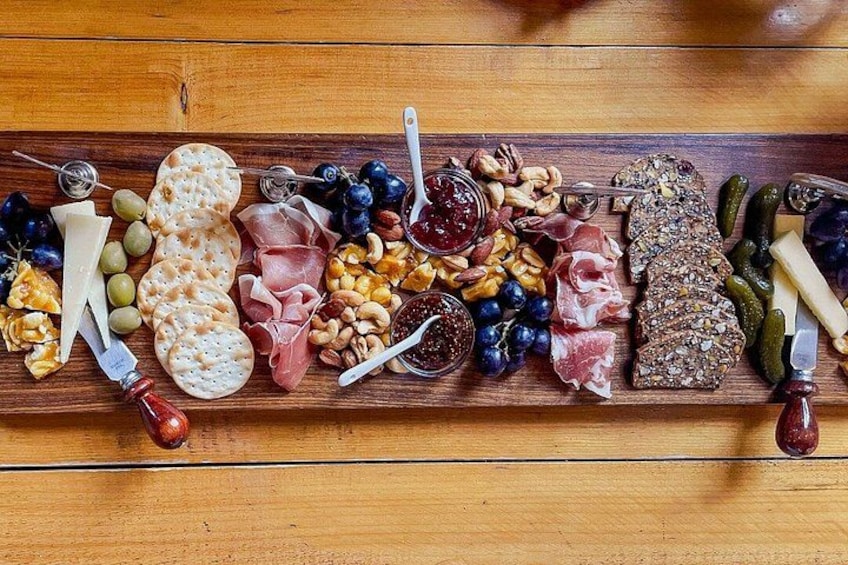 A wooden board with various cheeses, meats, nuts, and fruits. 2