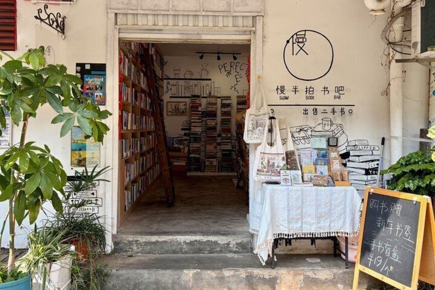 A bookstore with a signboard, bookshelves, and a table with books and bags. 4