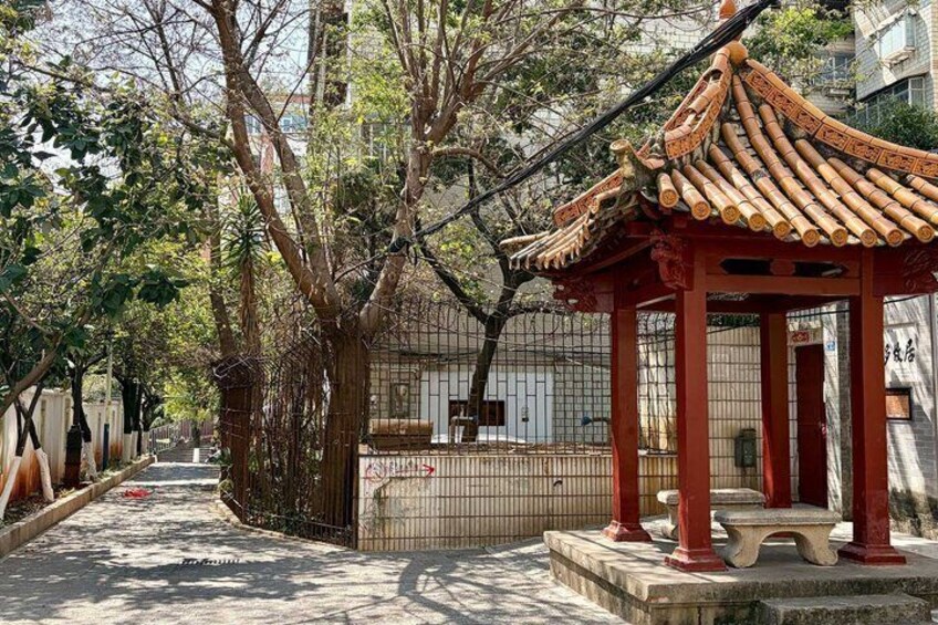 A traditional Chinese pavilion with a tiled roof, surrounded by trees and a fence. 5
