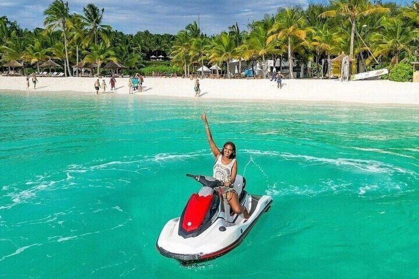 A person jet-skiing on turquoise water with a beach and palm trees in the background. 3