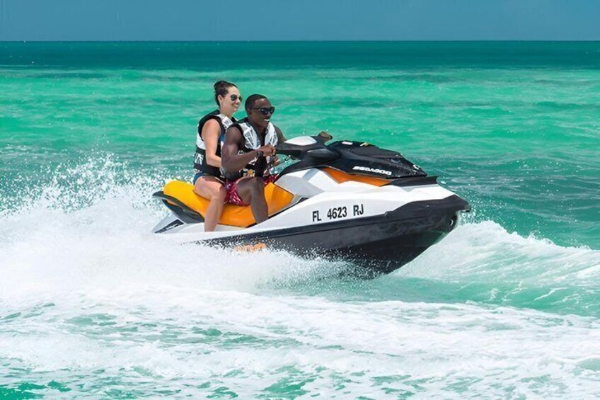 A jet ski with two people on it, moving through turquoise water. 2