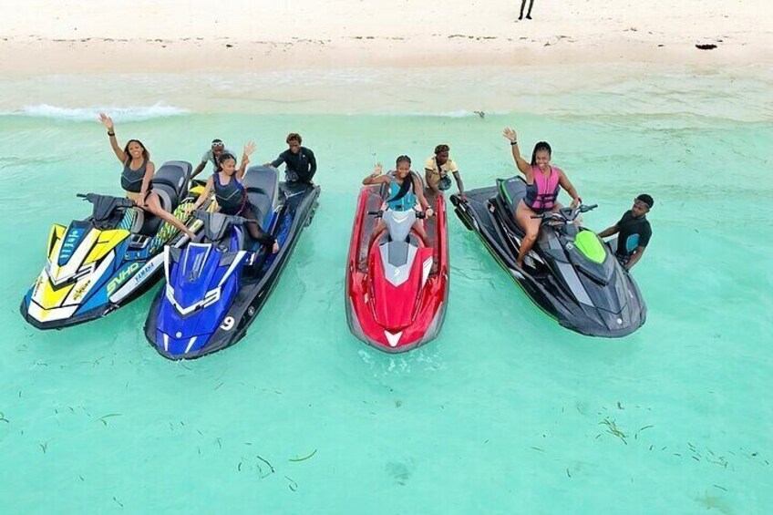Four jet skis on a beach with people on them. 5