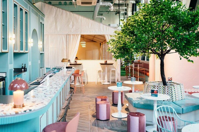 A restaurant with a bar area, tables, chairs, and a small tree. 4