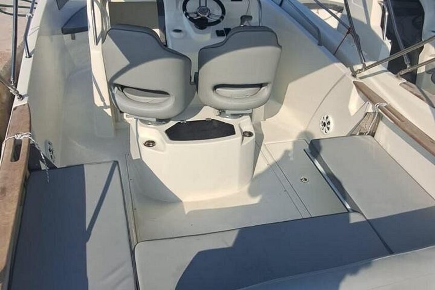 A boat's interior with a steering wheel, two seats, and a control panel. 2