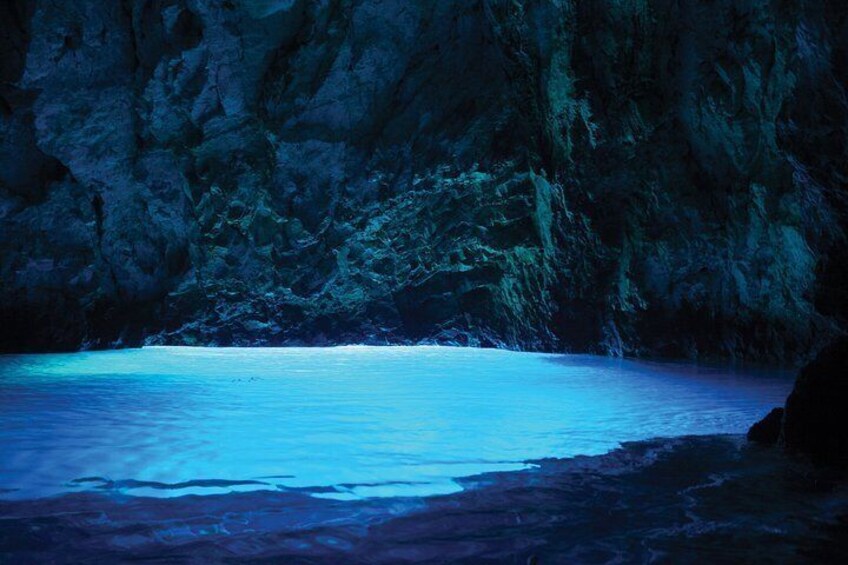 A cave entrance with a blue-lit interior and a calm sea. 1
