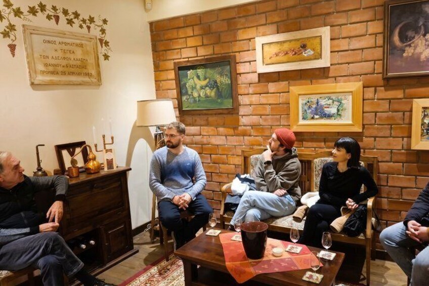 A group of people sitting around a table in a room with brick walls, wooden furniture, and framed artwork. 2
