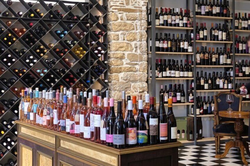 A wine cellar with numerous bottles on shelves and a counter with more bottles. 5