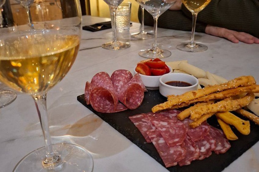 Une table sur laquelle on trouve une variété d’aliments, notamment des tranches de salami, des gressins et un petit bol de sauce. 2