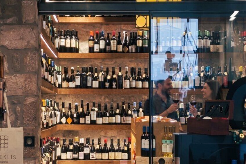 A wine shop with shelves of wine bottles and a person behind the counter. 1