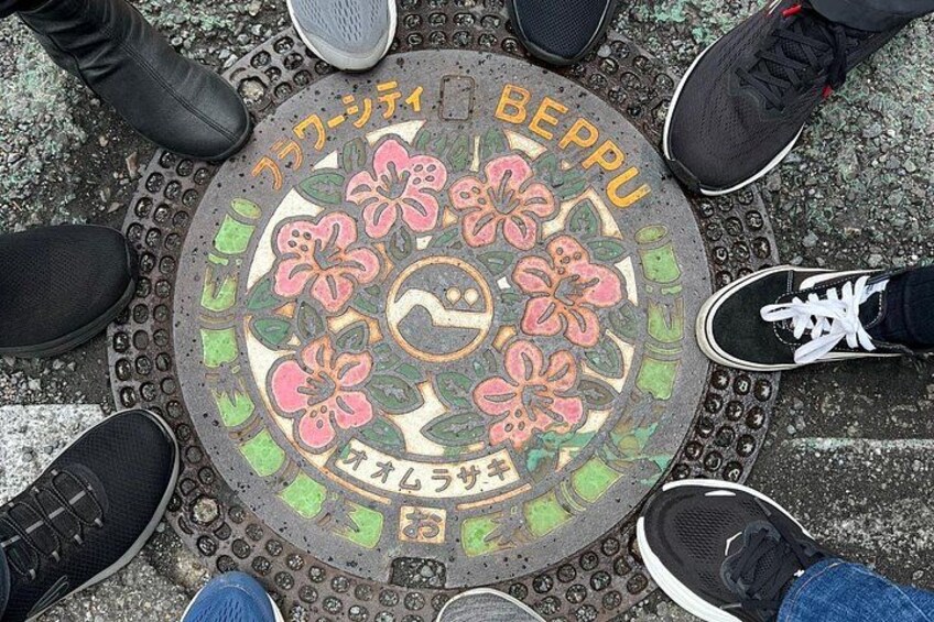 A circular manhole cover with floral patterns and Japanese text. 3