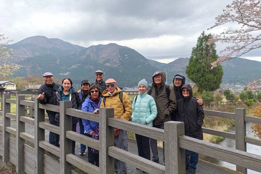 A group of people standing on a wooden bridge with mountains in the background. 4